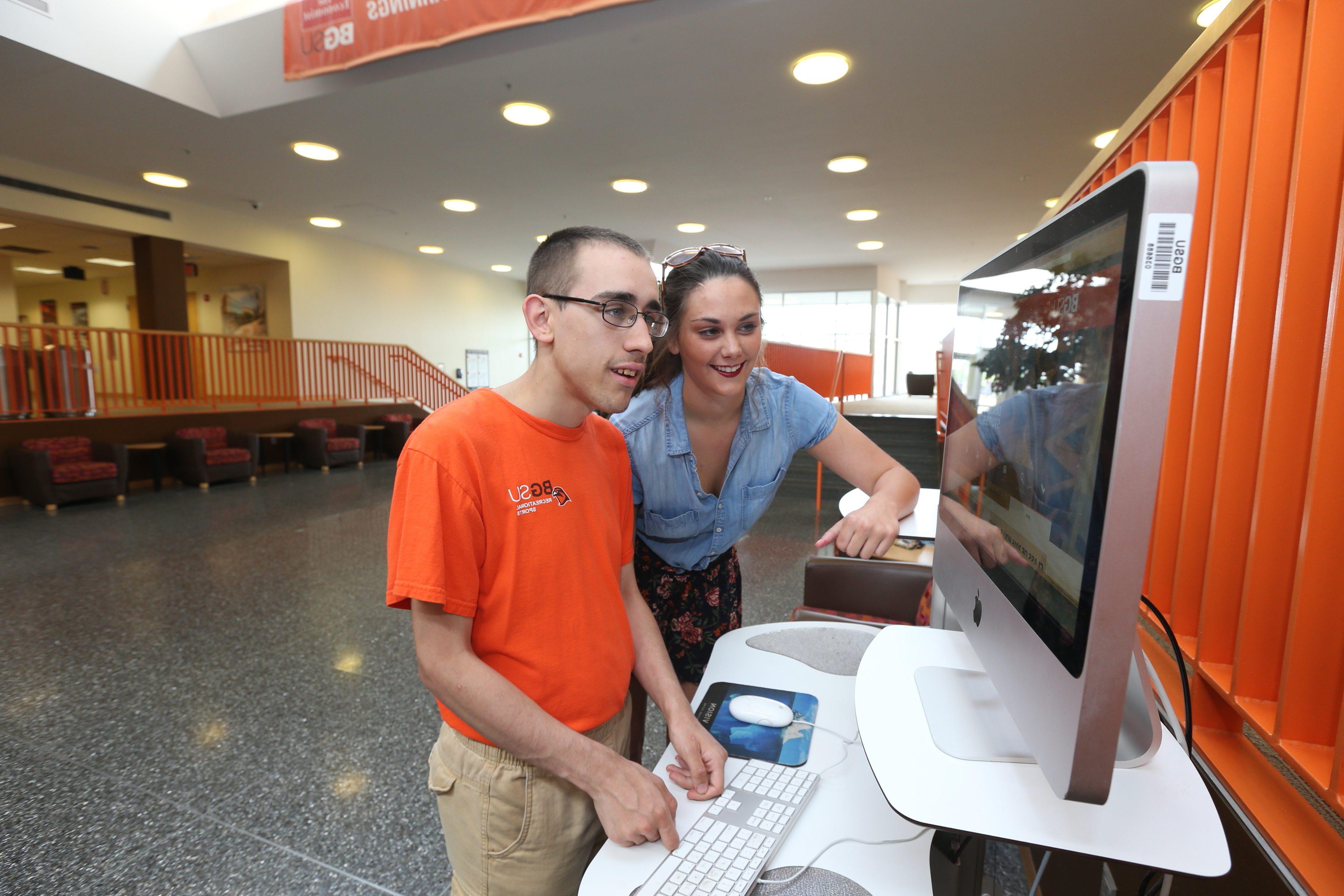A female student in the BGSU master’s program in special education with a specialization in autism spectrum disorders works on a computer with a young man with autism.